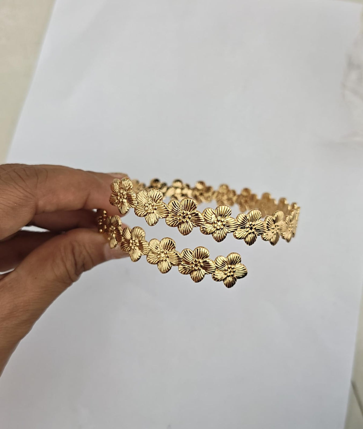 gold-plated, open-cuff bracelet textured floral motifs.