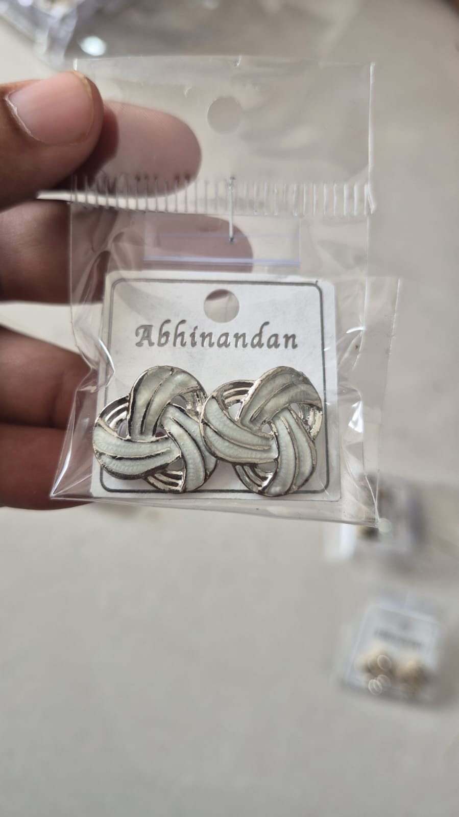 silver-toned intertwined knot design accented with white enamel earring