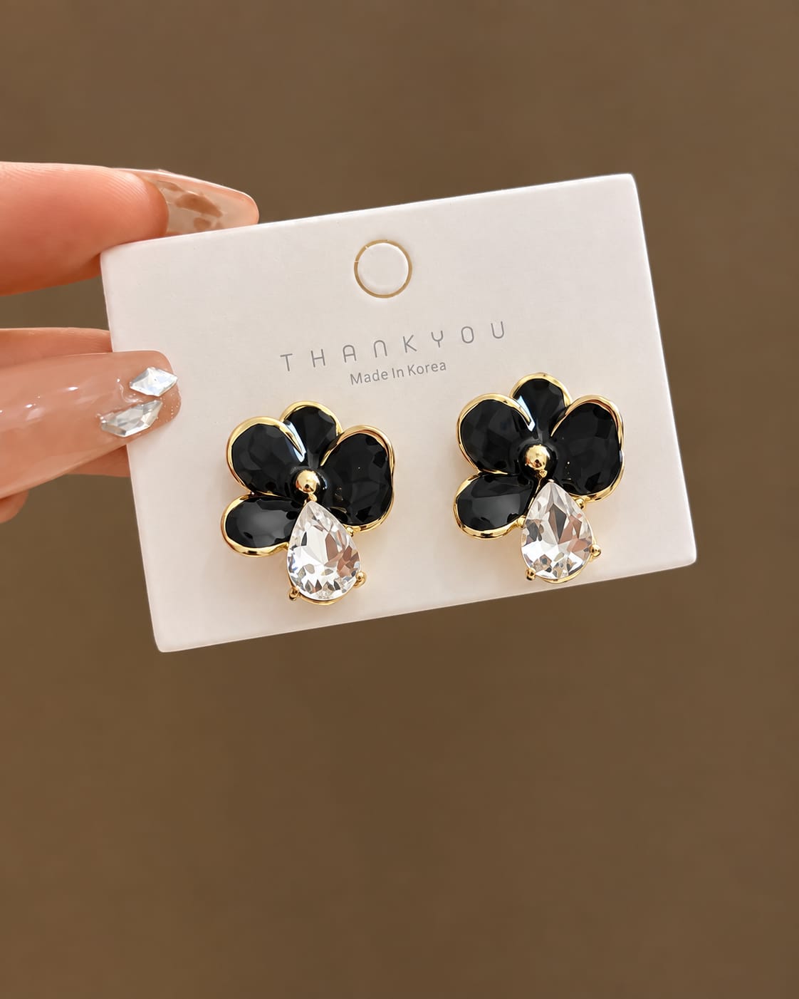 black glossy floral earrings with a dangling teardrop crystal.