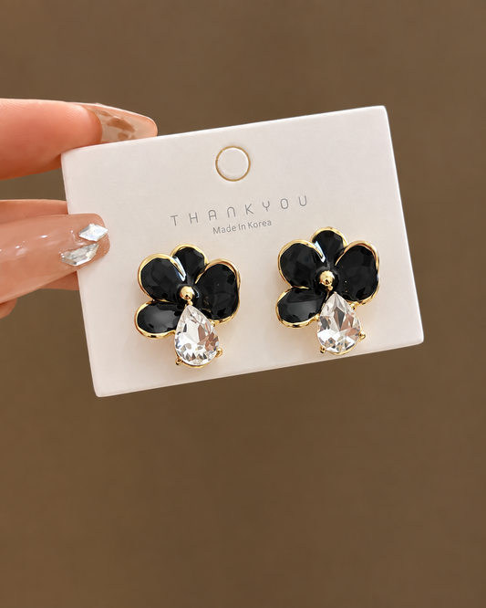 black glossy floral earrings with a dangling teardrop crystal.