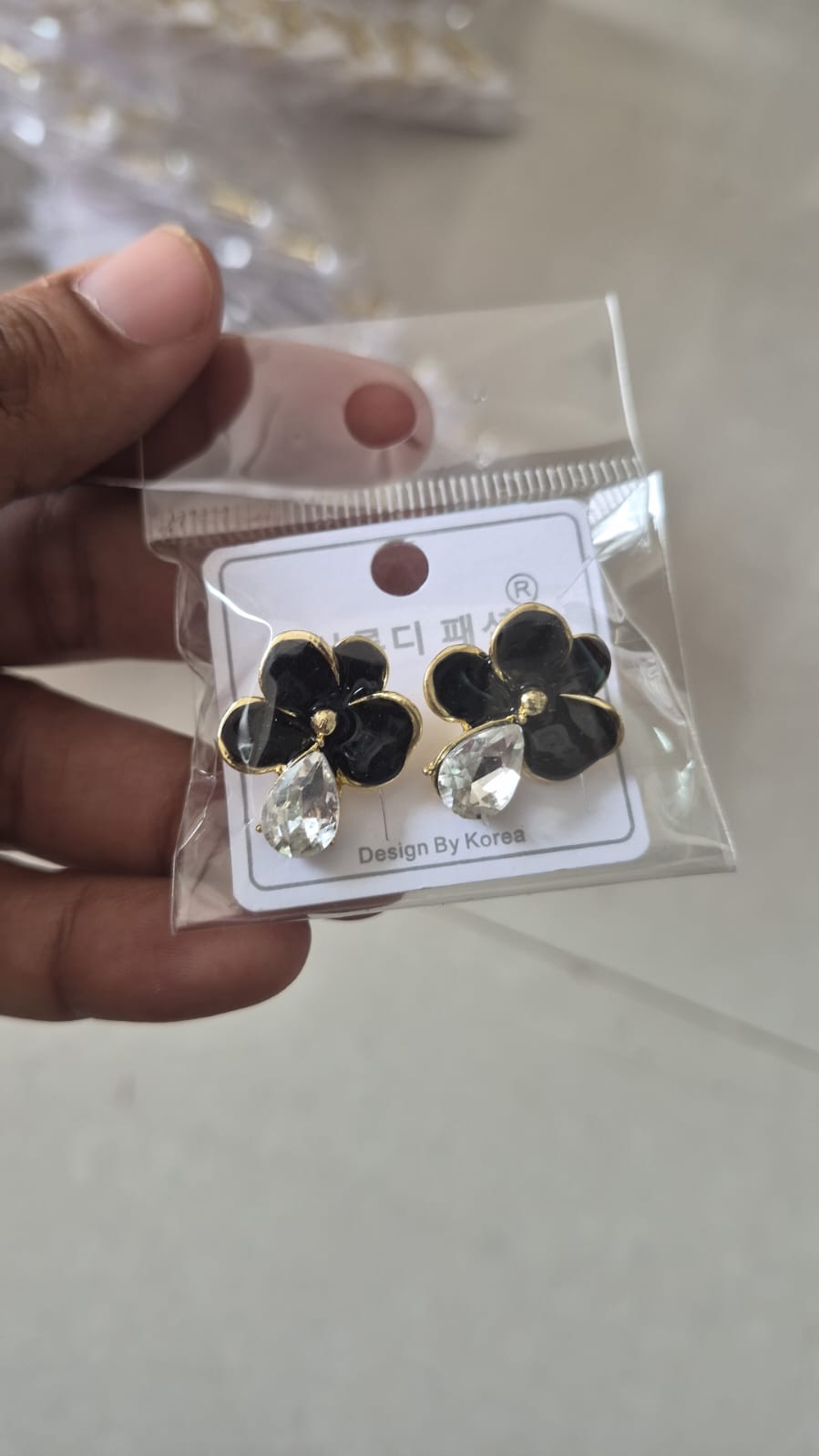 black glossy floral earrings with a dangling teardrop crystal.