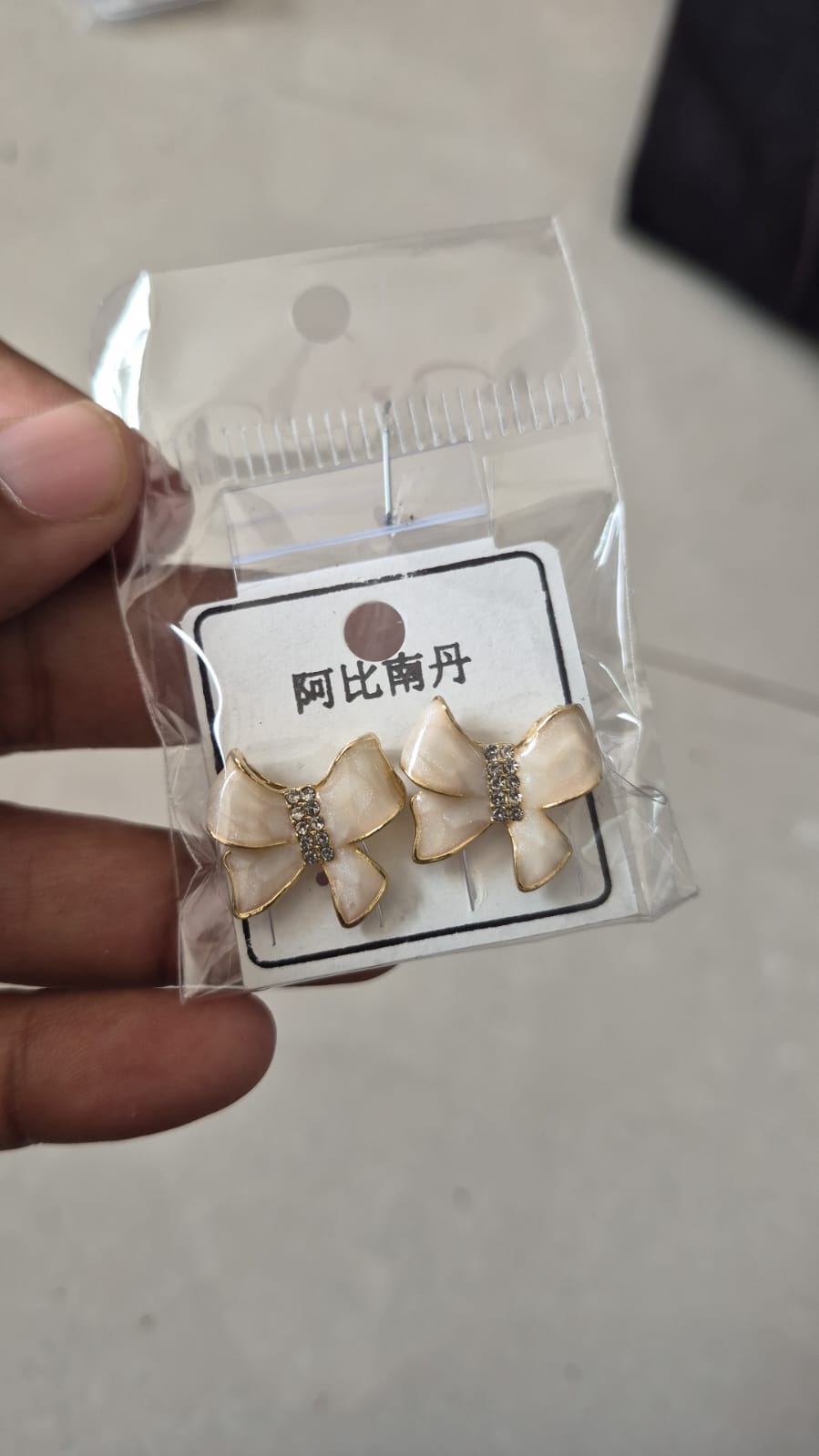 ivory enamel bow-shaped stud earrings with rhinestone accents.