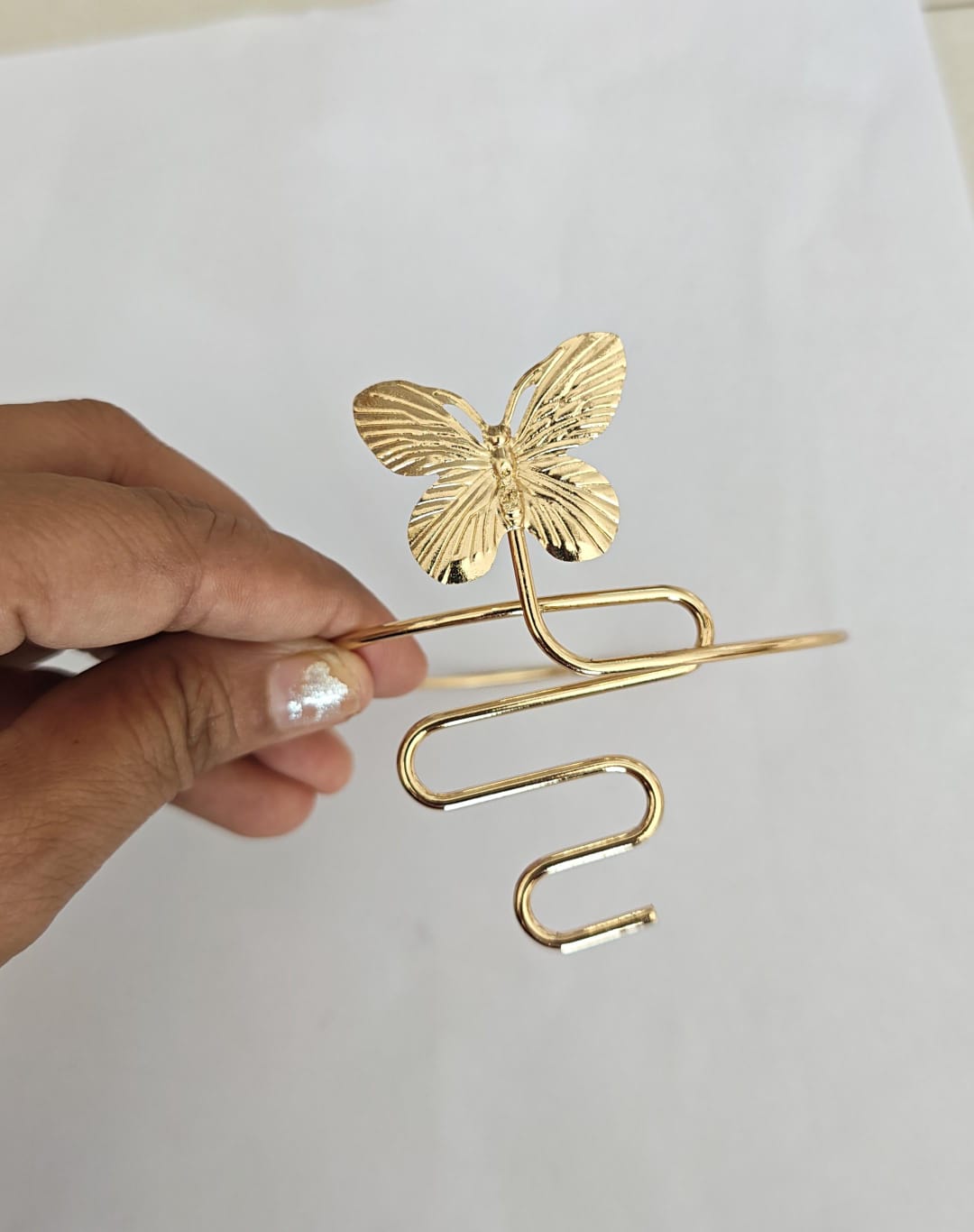 butterfly charm attached to an open, adjustable spiral armcuff