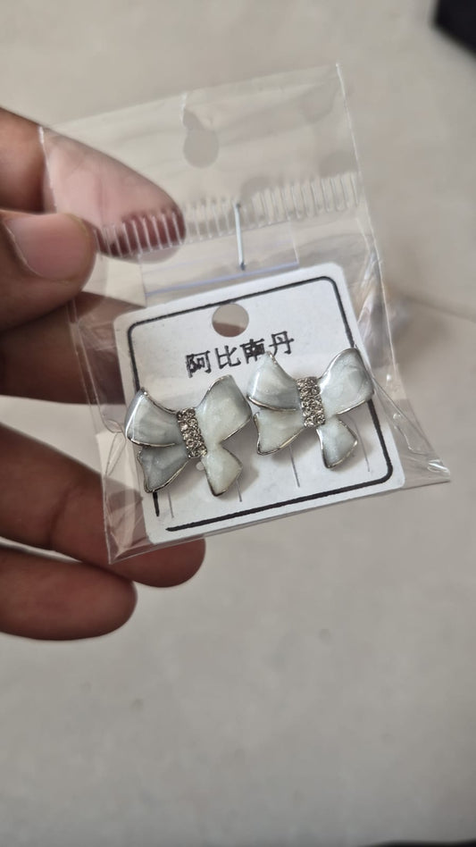 ivory enamel bow-shaped stud earrings with rhinestone accents.